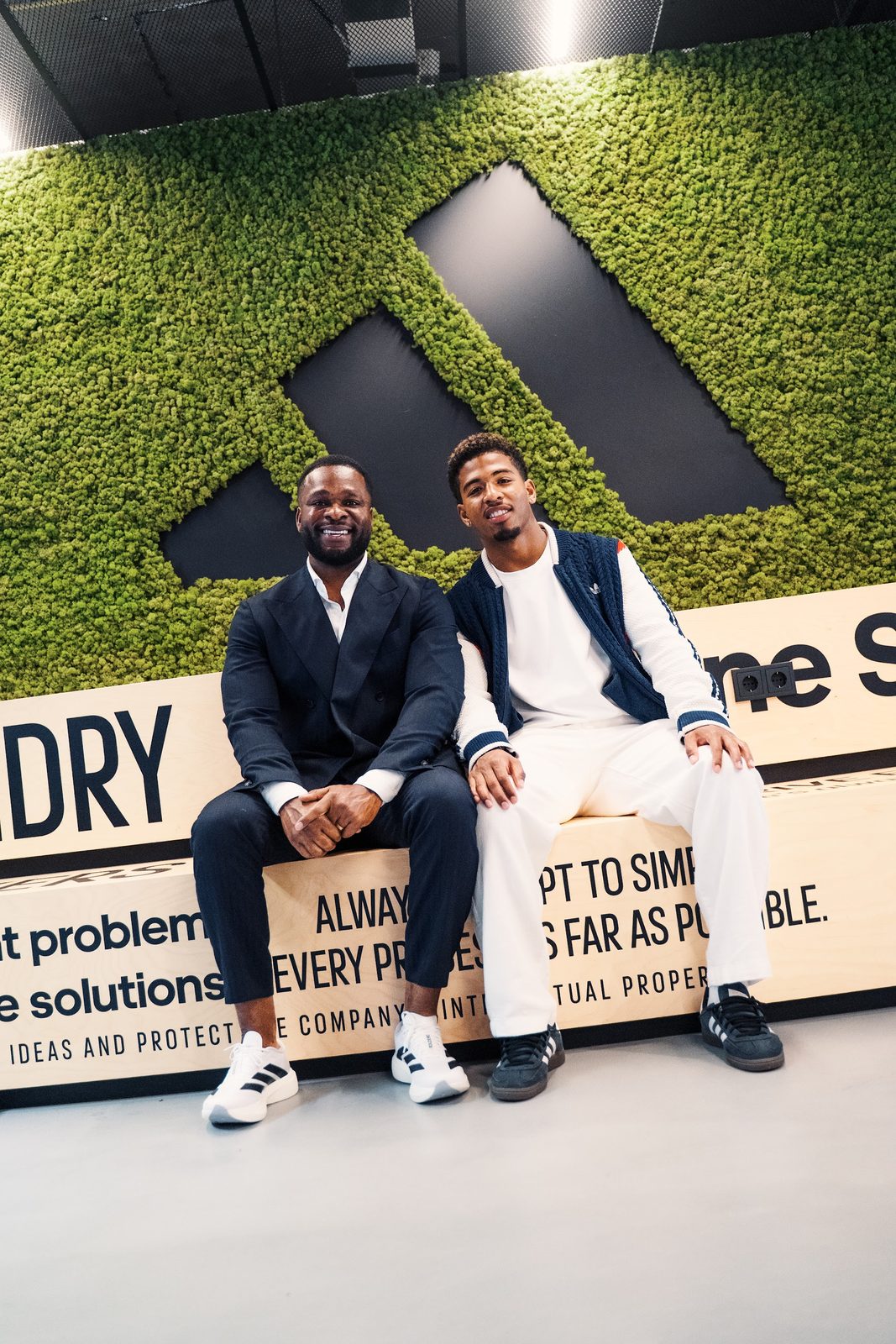 AAM Agency founder in a black suit seated with Shurandy Sambo at the adidas signing
